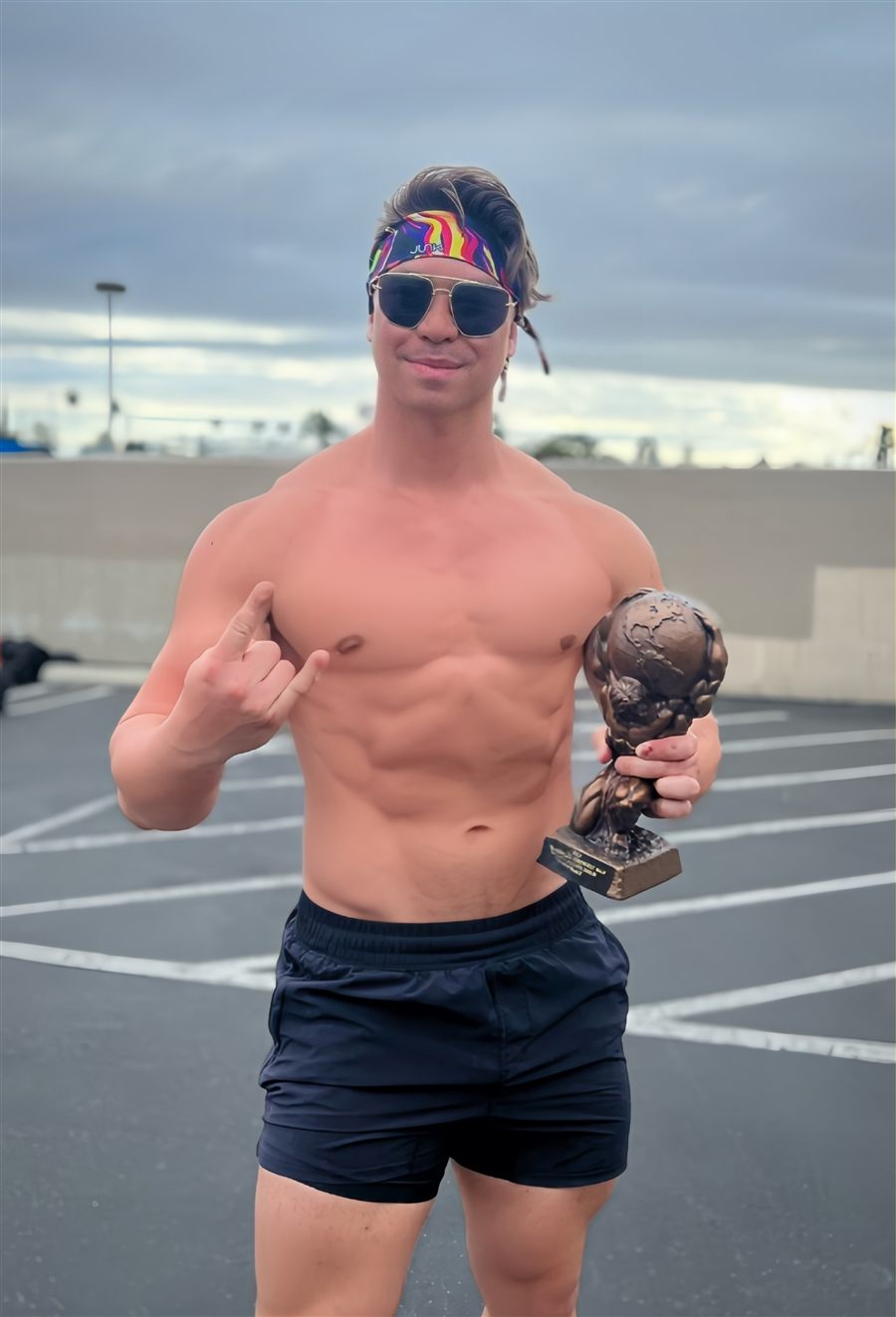 Alex Huang holding a strongman competition trophy